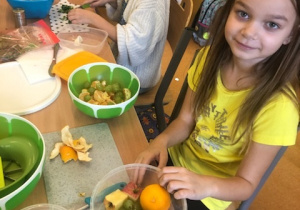 Dziewczynki przygotowuja sałatkę z winogron, jabłek i pomarańczy.
